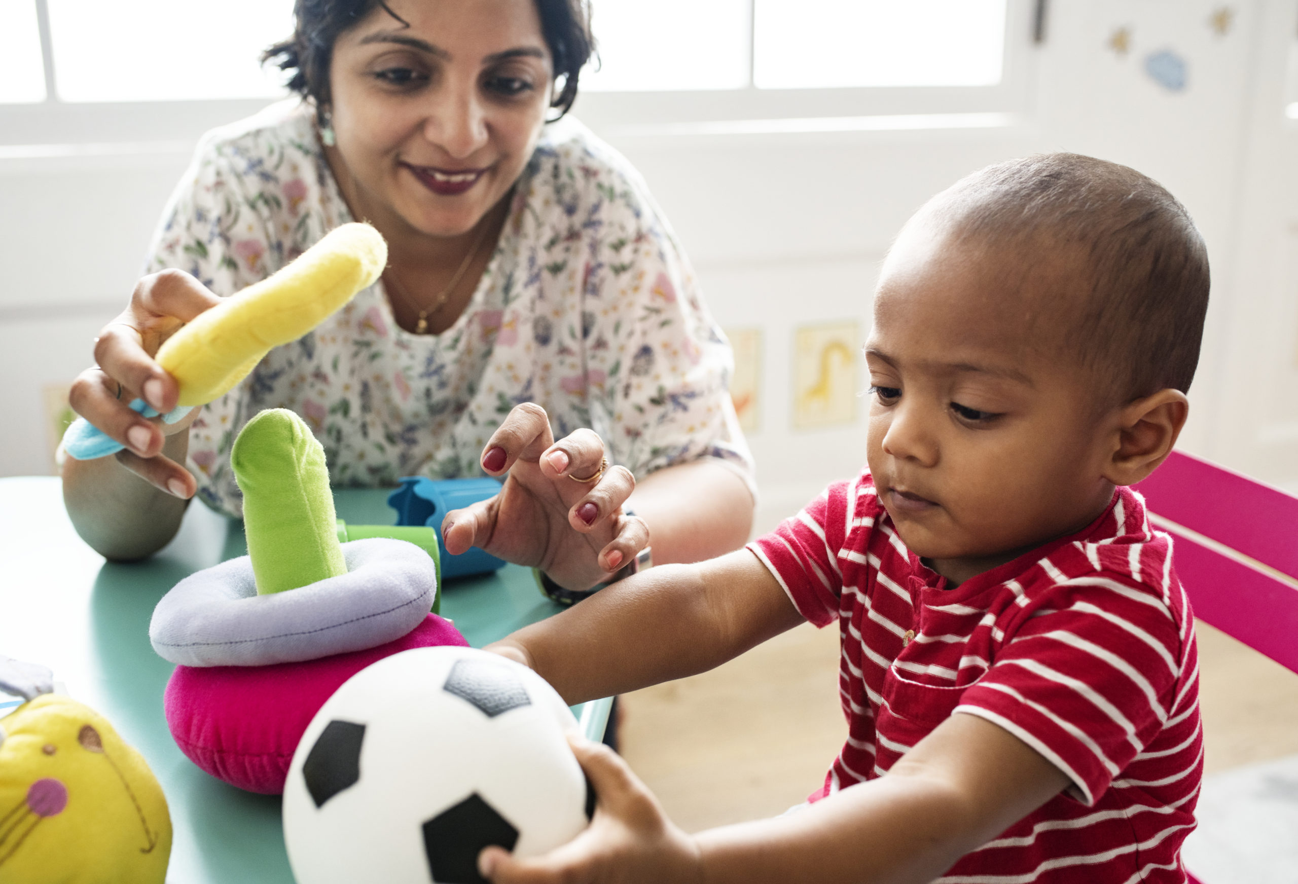 Nursery child playing with teacher in the classroom